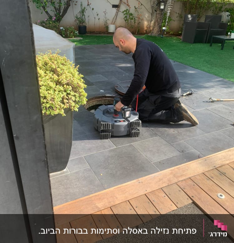 אדם עובד עם כלי עבודה על צינור בחצר